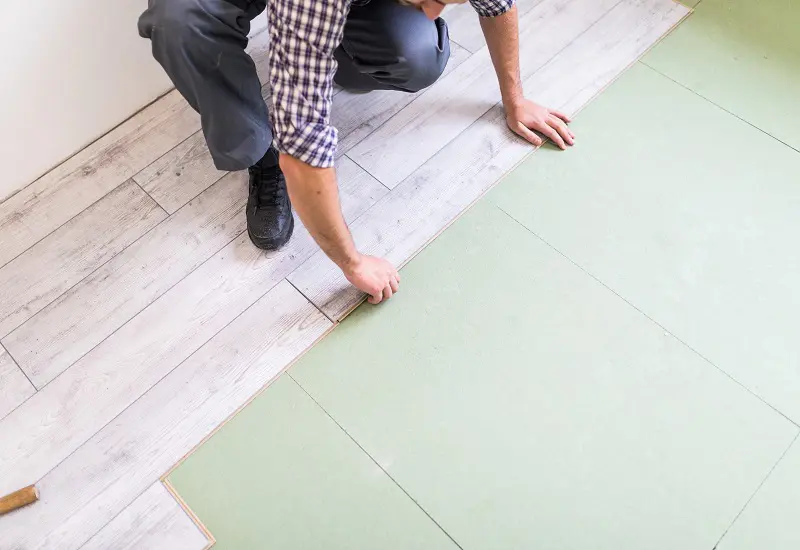 worker processing a floor with bright laminated flooring boards