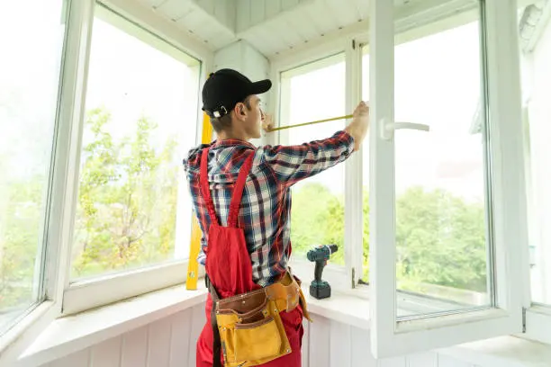 Man measuring window prior to installation of roller shutter outdoors