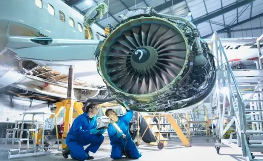 Aircraft engineers inspecting jet engine in aircraft maintenance factory