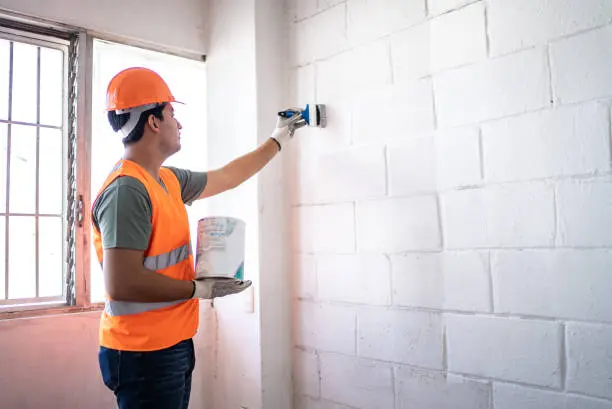Young painter   construction worker painting a wall indoors