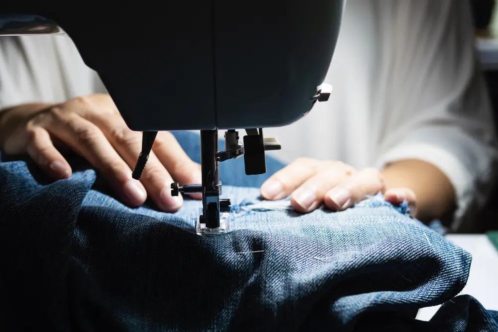 woman doing jeans patchwork using sewing machine home diy sewing concept